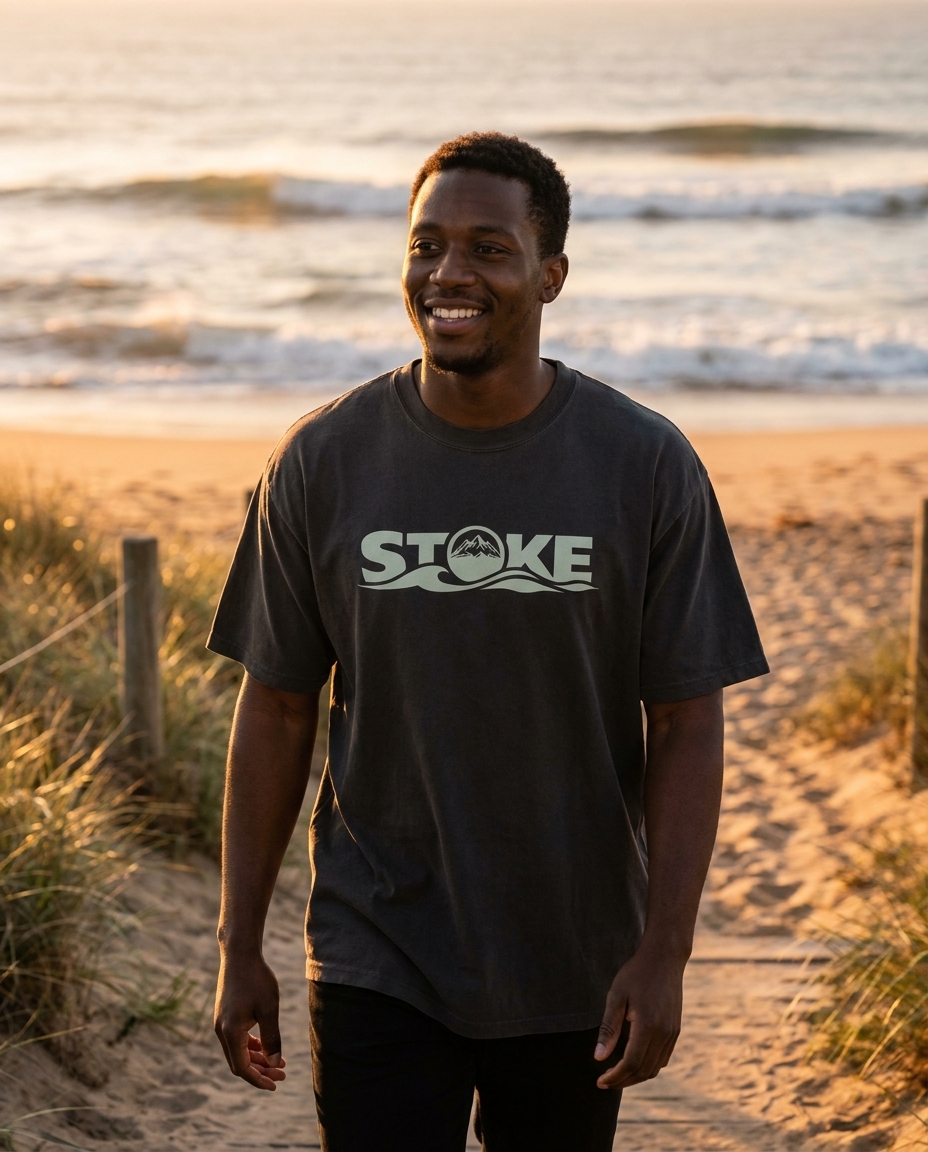 Man walking a beach at golden hour in the unisex STOKE Heavyweight Trail Tee in Faded Black
